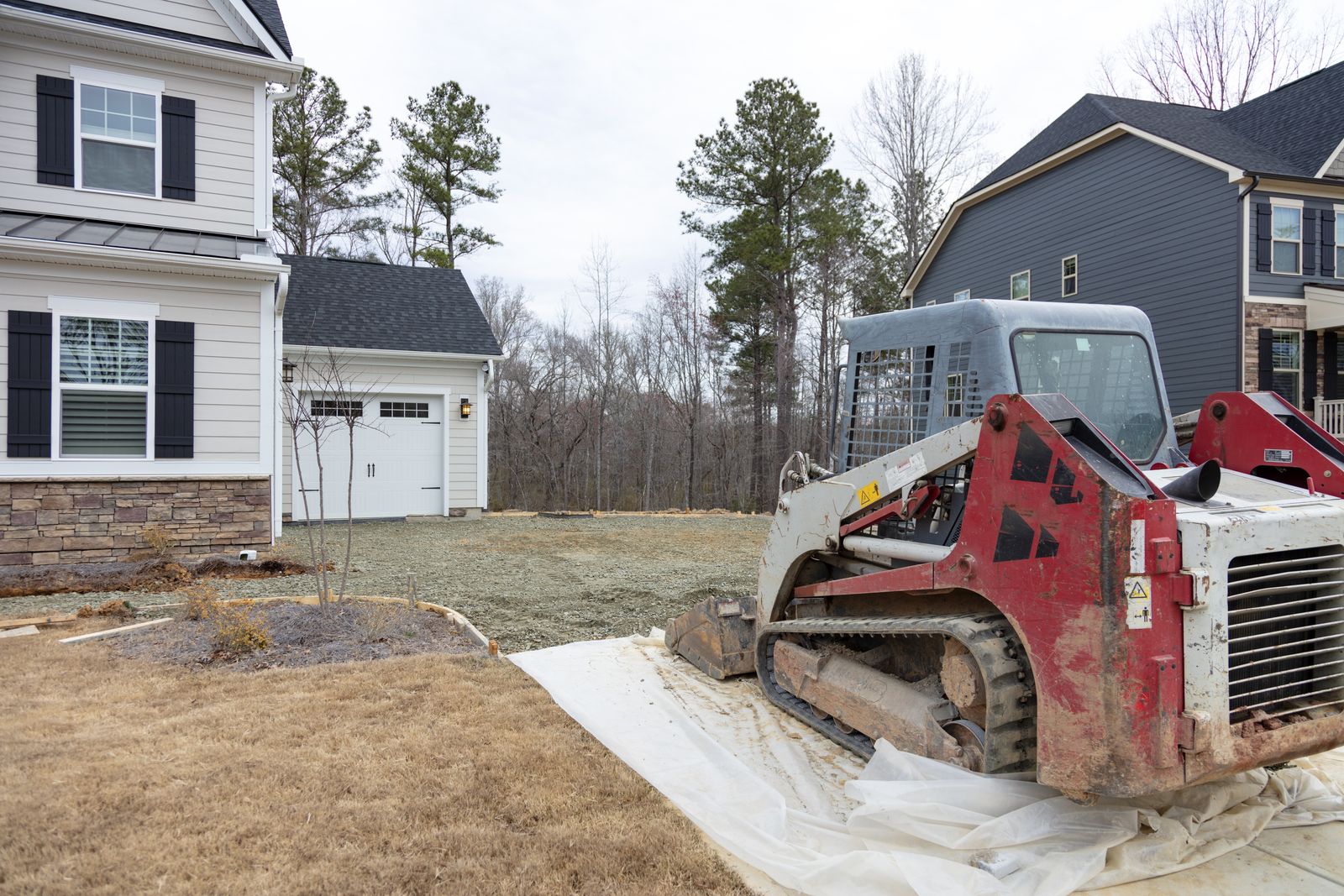 Contractor grading a new home's yard with a skid steer