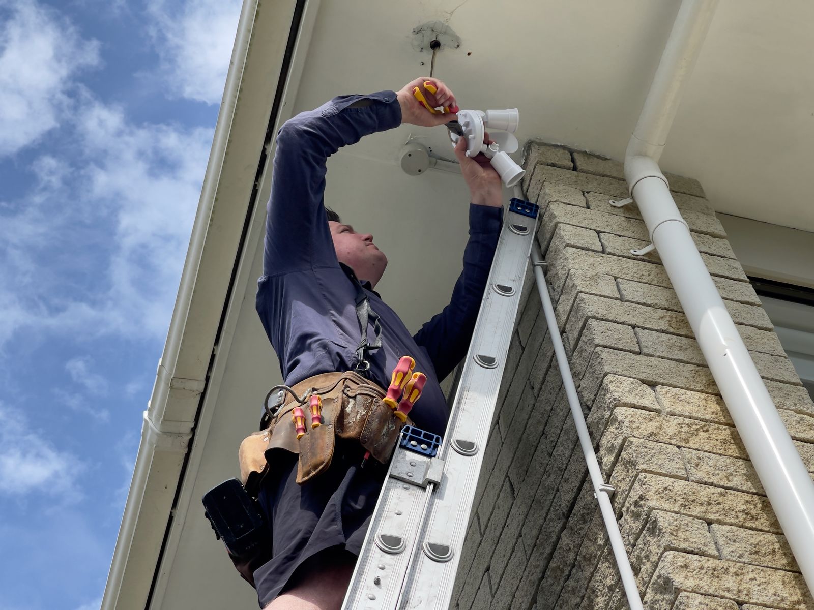 Electrician on a ladder installing an exterior light