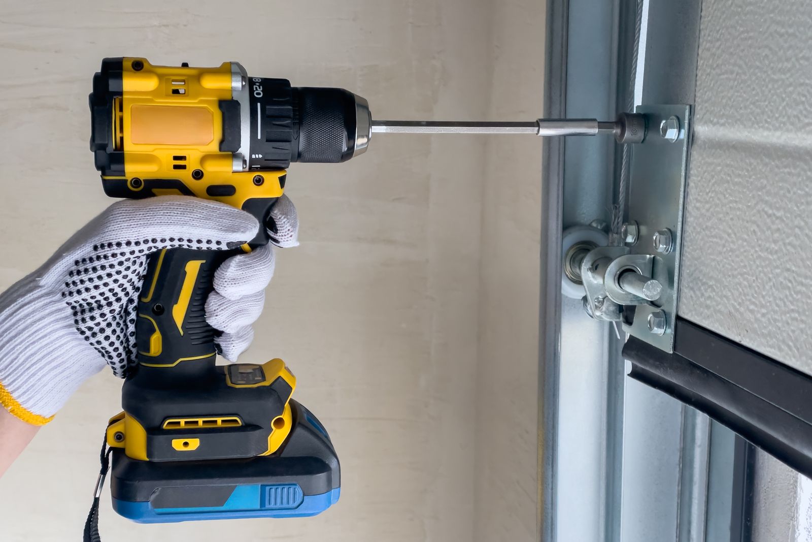 Garage door technician fastening a door track with a drill